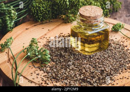 Dillsamenöl, Bio-Dillpflanzenblumen und trockene Samen, indische traditionelle Heilkräuter und Gewürz auf Holztisch Stockfoto