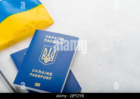 Gelb-blaue ukrainische Flagge und zwei biometrische ukrainische Pässe auf hellem Hintergrund. Persönliche Identifikation, Tourismus, Reisen, Flüchtlinge, Krieg in Ukr Stockfoto