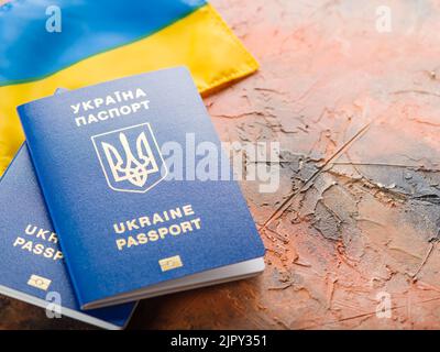 Auf einem orangefarbenen Hintergrund die ukrainische Staatsflagge und zwei ukrainische biometrische Pässe. Staatsbürgerschaft der Ukraine, Patriotismus, Demokratie, Freiheit, indep Stockfoto