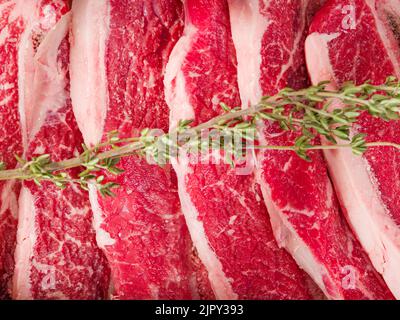 Makroaufnahme. Hausgemachte Steaks aus biologischem Fleisch vom Bauernhof - Schweinefleisch, Rindfleisch und ein duftender Rosmarinzweig. Köstliche Fleischrezepte. Restaurant, Hotel, CAF Stockfoto