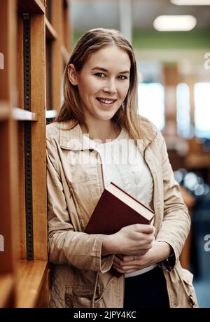 Ich habe die Bücher, die ich brauche. Porträt eines Studenten, der in einem Korridor auf dem Campus steht. Stockfoto
