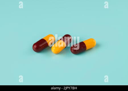 Drei gelb-braune Kapseln auf cyanfarbenem Hintergrund Stockfoto