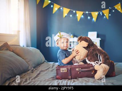 Segeln Sie das Meer von Make Believe. Porträt eines entzückenden kleinen Jungen, der als Seemann verkleidet ist und zu Hause auf dem Bett spielt. Stockfoto