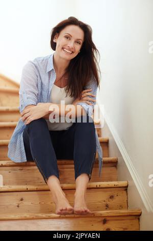 Das Wochenende barfuß auf der Treppe verbringen. Eine junge Frau, die zu Hause auf der Treppe sitzt. Stockfoto