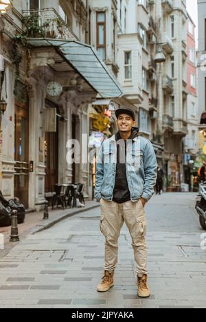 Mann mit Jeansjacke lächelt zum Ganzkörperportrait der Kamera Stockfoto