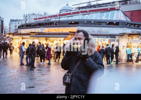 Mann, der gegrillten Mais isst, kaufte er vom Straßenverkäufer Stockfoto
