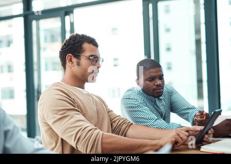 Zwei junge Designer arbeiten an einem digitalen Tablet in einem Büro. Stockfoto