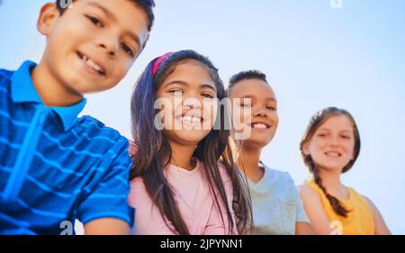 Mit großen Freunden wie diesen gut immer lächeln. Porträt einer vielfältigen Gruppe von Kindern draußen. Stockfoto