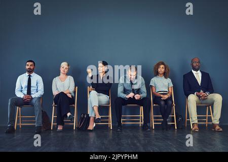 Wer wird der erfolgreiche Kandidat. Eine Gruppe von gut gekleideten Geschäftsleute in der Schlange sitzen, während warten, um Interview zu sein. Stockfoto