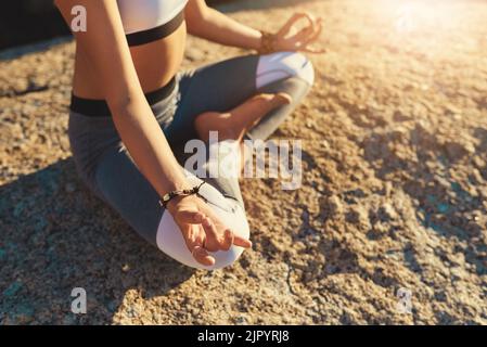 Je früher man anfängt, desto besser. Eine junge Frau, die am Strand Yoga macht. Stockfoto