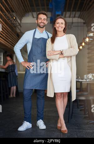 Stolze Geschäftspartner. Porträt zweier junger Unternehmer, die in ihrem Café stehen. Stockfoto
