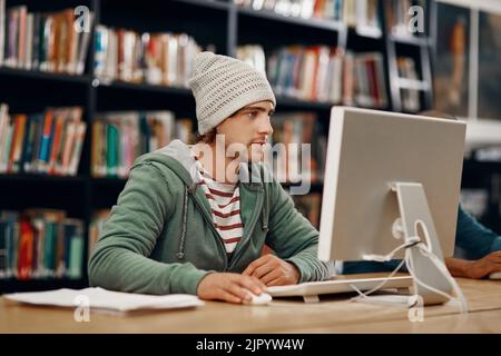 Ein junger Student der Universität, der in der Bibliothek studiert. Stockfoto