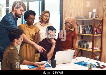 Sie haben die Fähigkeiten und das Know-how erworben, um darüber hinaus erfolgreich zu sein. Eine vielfältige Gruppe von Geschäftsleuten, die an einem Laptop in einem Büro zusammenarbeiten. Stockfoto