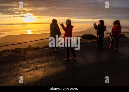 Touristen, die den Sonnenaufgang vom Gipfel des kunanyi/Mt Wellington in Hobart Tasmanien aus beobachten (Höhe 1271 Meter über dem Meeresspiegel) Stockfoto