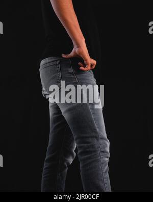 Taille des Mannes mit Jeans und schwarzem Hemd. Mann auf schwarzem Hintergrund mit schwarzem T-Shirt und Jeans. Hochwertige Fotos Stockfoto