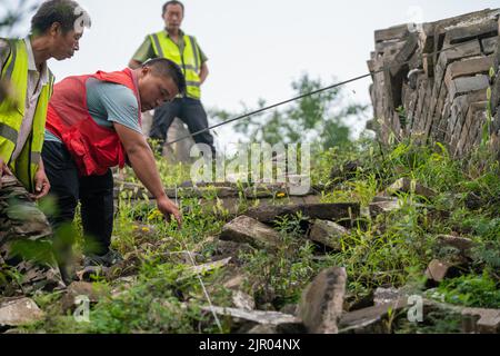 (220821) -- PEKING, 21. August 2022 (Xinhua) -- Techniker Yang Zhanjie (C) grenzt das Ausgrabungsgebiet zu archäologischen Zwecken am Jiankou-Abschnitt der Großen Mauer in Peking, der Hauptstadt Chinas, ab, 17. August 2022. Der Jiankou-Abschnitt der Großen Mauer, einst unter den Wanderern als „verlassene große Mauer“ bekannt, liegt im Vorort Huairou in Peking und gilt als einer der gefährlichsten Teile der Reliquie. Ein Restaurierungsprojekt, das sich hauptsächlich auf eine 1.678 Meter lange Wand mit 8 Wachtürmen im westlichen Teil des Abschnitts Jiankou konzentriert, wird voraussichtlich bis Ende Oktober abgeschlossen sein Stockfoto