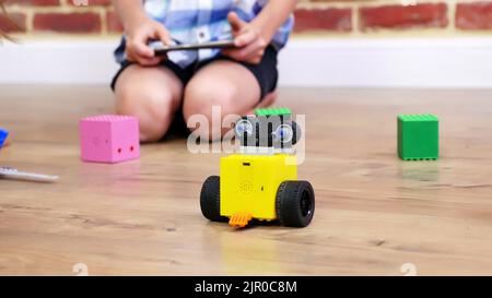 Nahaufnahme, Funkroboter bewegt sich auf dem Boden, kleine Genies, Kinder spielen elektronische Roboter, Autos, modernes Spielzeug auf Funksteuerung. Neue Technologien in der Gaming-Industrie. Hochwertige Fotos Stockfoto