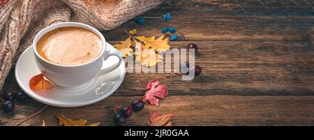 Gemütliche Herbstkomposition mit Kaffee, Pullover und Laub. Stockfoto