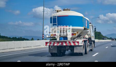 Blauer Zement-LKW auf einer Autobahn unter einem blauen Himmel mit weißen Wolken. Stockfoto
