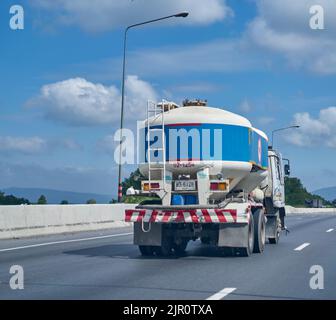 Blauer Zement-LKW auf einer Autobahn unter einem blauen Himmel mit weißen Wolken. Stockfoto