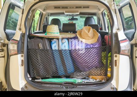 Ein Auto, das bereit für die Reise verpackt ist, mit Sonnenhüten und Koffern. Stockfoto