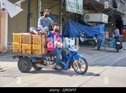 Mitarbeiter auf einem Obst- und Gemüsemarkt in Thailand, die Obstkisten auf einem Motorrad transportieren. Stockfoto