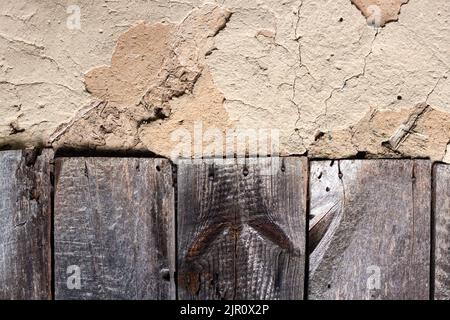 Alte Kohlenwand mit rissiger Oberfläche und alten Holzbrettern. Vintage Hintergrund für Designzwecke Stockfoto
