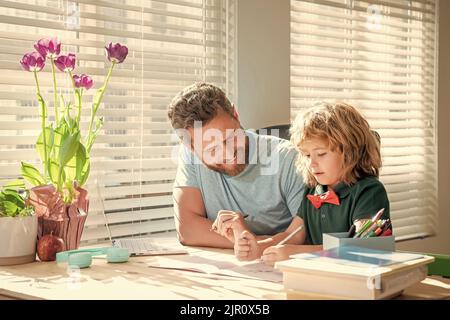 Glücklicher bärtiger Vater, der Schulaufgaben mit seinem Sohn im Klassenzimmer schrieb und Heimschooling machte Stockfoto