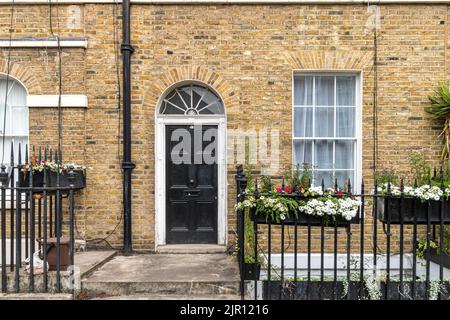 Eine schwarze Eingangstür mit einer Lüfterbeleuchtung darüber am Eingang eines Wohnhauses in der Warren Street in Fitzrovia , London W1 Stockfoto