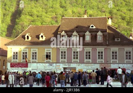 Brasov, Rumänien, April 1990. Nach der antikommunistischen Revolution von 1989 brachen im ganzen Land Proteste gegen die ehemaligen kommunistischen Beamten aus, die sofort die Macht ergriffen hatten. Auf dem zentralen Platz von Brasov lesen die Menschen Plakate und Transparente, die die neue Partei an der Macht, F.S.N., verurteilten Stockfoto