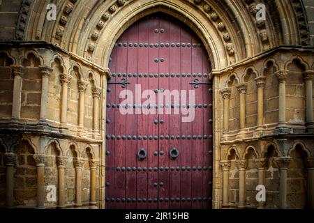 Fassade der Kirche San Pablo im romanischen Stil von beda, Jan, Spanien, rote Holztür, Säulen und Spitzbögen Stockfoto