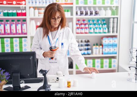 Frau mittleren Alters Apotheker Scannen Pillen Flasche in der Apotheke Stockfoto
