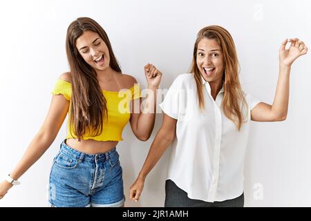 Mutter und Tochter stehen zusammen über isoliertem Hintergrund, tanzen fröhlich und fröhlich, lächeln sich bewegend lässig und selbstbewusst und lauschen m Stockfoto