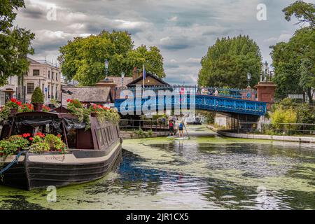 Paddelboarding für zwei Personen, Pass unter der Westbourne Terrace Road Bridge, einer markanten blau bemalten Brücke in Little Venice, Maida Wale, London Stockfoto