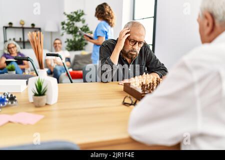 Zwei pensionierte Männer konzentrieren sich auf das Schachspiel im Heim der Krankenschwester. Stockfoto