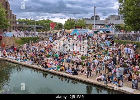 Menschenmassen, die an einem warmen Sommerabend in London auf den Stufen am Kanal des Regent's in der Nähe des Granary Square am Kings Cross sitzen Stockfoto