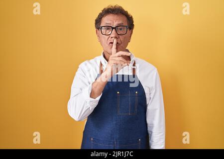 Mittelalter hispanischer Mann trägt professionelle Koch Schürze fragen, ruhig mit Finger auf den Lippen zu sein. Stille und geheime Konzept. Stockfoto