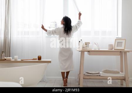 Junge Schwarze Frau Öffnen Vorhänge Während Der Herstellung Morgen Schönheit Routine Im Badezimmer Stockfoto
