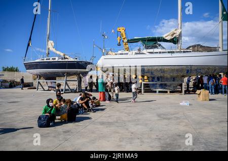 Roccella Jonica, Italien. 21. August 2022. Migranten sahen in der Nähe von beschlagnahmten Booten warten. Die italienische Küstenwache führte eine Rettungsaktion von Berichten zufolge 75 Migranten auf einem Boot durch, das sich 107 Seemeilen von der südlichen Stadt Roccella Jonica (Italien) entfernt befindet. Mitglieder des Roten Kreuzes und Ärzte ohne Grenzen leistten lokale Hilfe. Kredit: SOPA Images Limited/Alamy Live Nachrichten Stockfoto