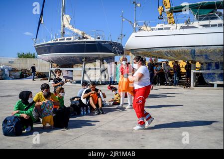 Roccella Jonica, Italien. 21. August 2022. Eine Dame vom Roten Kreuz sah, wie sie den Migranten Lebensmittel verteilte, die auf Hilfe warteten. Die italienische Küstenwache führte eine Rettungsaktion von Berichten zufolge 75 Migranten auf einem Boot durch, das sich 107 Seemeilen von der südlichen Stadt Roccella Jonica (Italien) entfernt befindet. Mitglieder des Roten Kreuzes und Ärzte ohne Grenzen leistten lokale Hilfe. Kredit: SOPA Images Limited/Alamy Live Nachrichten Stockfoto