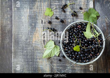 Rohe Bio-Beeren. Das Konzept der Vitamin-C-Nahrung. Frische schwarze Johannisbeeren auf einem Holztisch im rustikalen Stil. Blick von oben. Speicherplatz kopieren. Stockfoto
