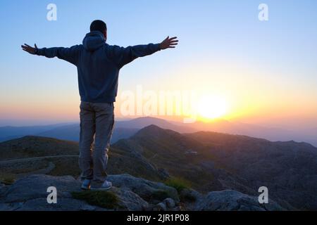Der Mensch trifft den Morgengrauen mit offenen Armen Stockfoto