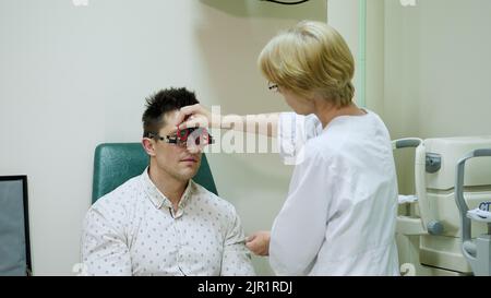 Weibliche Optometristin macht Sehtests für Patienten im Krankenhaus mit Phoropter, optometristischer Testrahmen, visuelle Inspektionsvorrichtung. Überprüft die Sicht in der Arztpraxis. Hochwertige Fotos Stockfoto