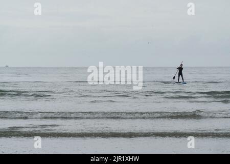 Wetter in Großbritannien, West Sussex, 21. August 2022: Wolken, Nieselregen und Höhen von 21 Grad halten Wanderer mit und ohne Hunde, Fußballer und Paddle-Boarder nicht davon ab, den Strand von West Wittering zu genießen. Im Gegensatz zu einigen anderen Stränden von Sussex ist das Wasser nicht unlimitiert, da es keine lokalen Abwasserleitungen gab. Trotz der niedrigen Wolke und des intermittierenden Nieselregen gibt es einen Blick auf die Isle of Wight und eine Regatta im Solent. Anna Watson/Alamy Live News Stockfoto