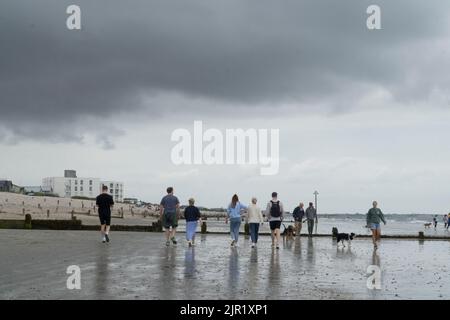 Wetter in Großbritannien, West Sussex, 21. August 2022: Wolken, Nieselregen und Höhen von 21 Grad halten Wanderer mit und ohne Hunde, Fußballer und Paddle-Boarder nicht davon ab, den Strand von West Wittering zu genießen. Im Gegensatz zu einigen anderen Stränden von Sussex ist das Wasser nicht unlimitiert, da es keine lokalen Abwasserleitungen gab. Trotz der niedrigen Wolke und des intermittierenden Nieselregen gibt es einen Blick auf die Isle of Wight und eine Regatta im Solent. Anna Watson/Alamy Live News Stockfoto