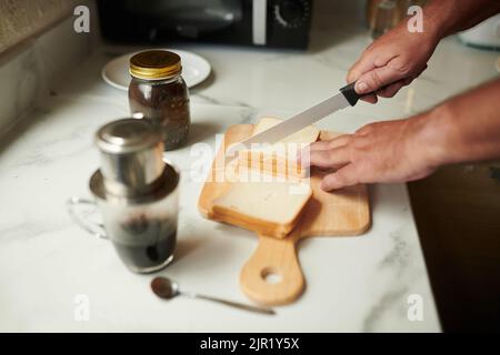 Hände eines älteren Mannes, der Kaffee und Sandwiches zum Frühstück zubereitet Stockfoto