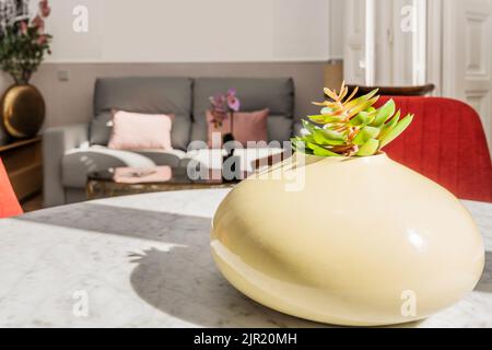 Herzstück mit einer künstlichen Pflanze in einem Wohnzimmer mit Sofas und mehr Pflanzen Stockfoto