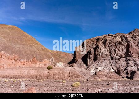 Der Mond über erodierten geologischen Formationen im Valle del Arcoiris oder im Rainbow Valley bei San Pedro de Atacama, Chile. Stockfoto