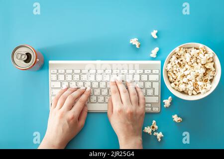 Filme mit Popcorn auf blauem Hintergrund ansehen, flach liegend. Stockfoto