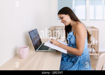 Fröhliche junge Erwachsene Studentin mit einem Videoanruf auf einem Laptop-Computer Stockfoto